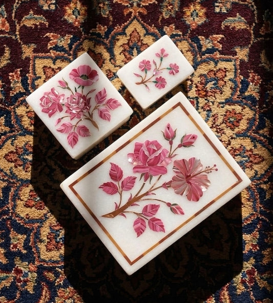 Vyasaara - Three decorative stone trays with floral designs on a patterned fabric background