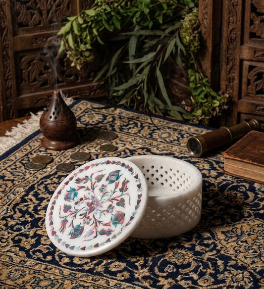 Vyasaara - Decorative incense holder with floral design on a patterned rug with incense and coins.