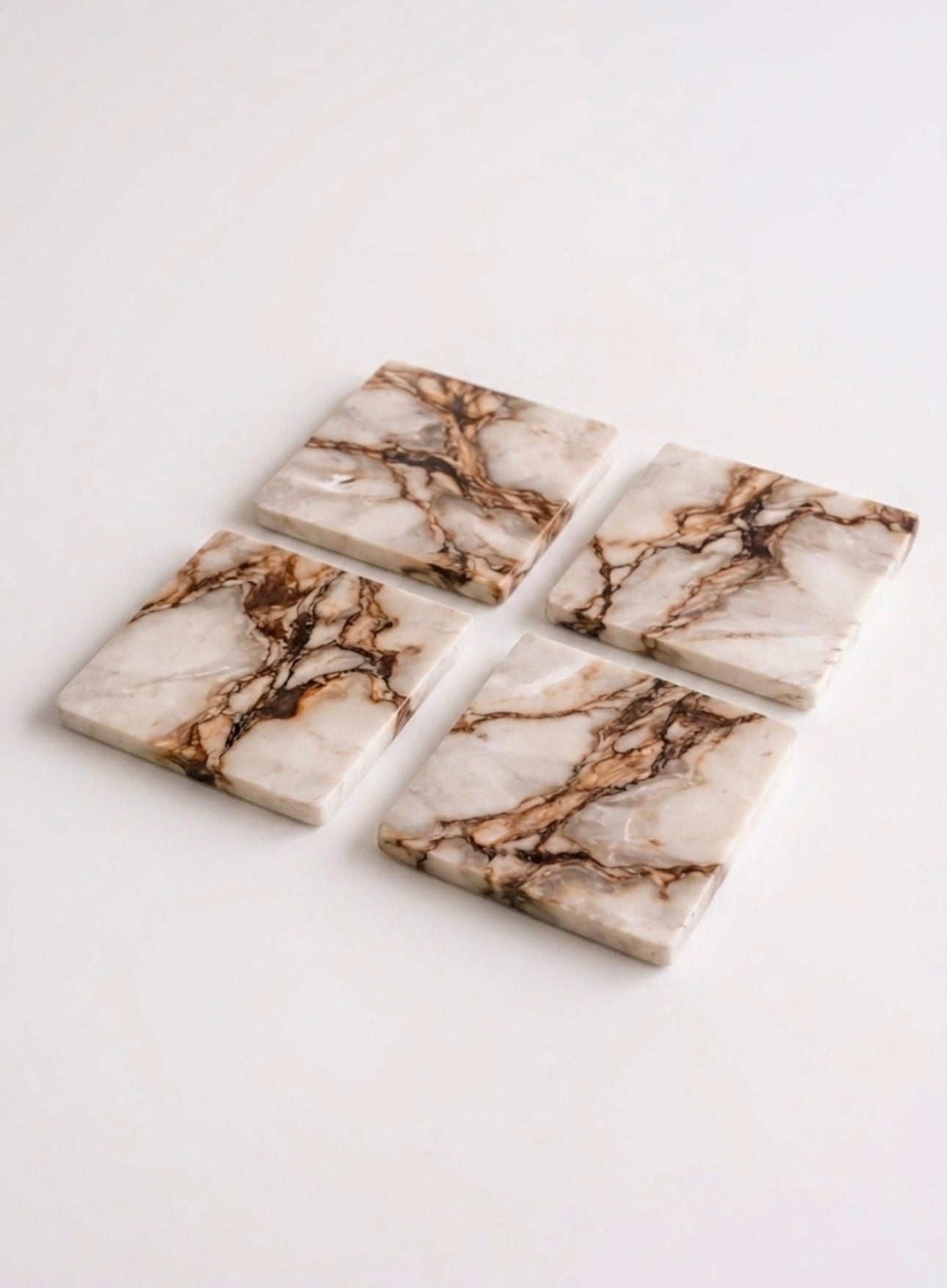 Vyasaara - Four marble-patterned coasters on a white background