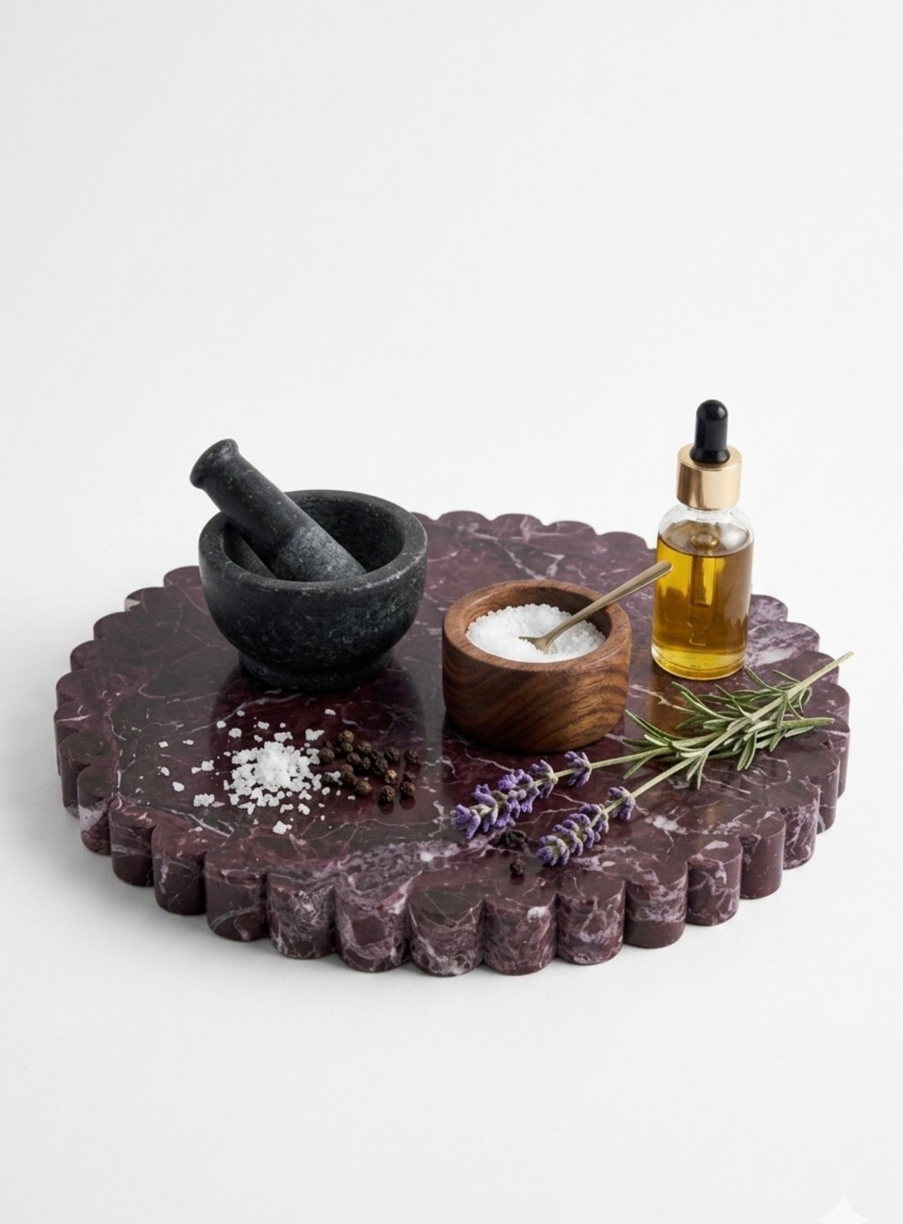 Decorative stone tray with a mortar and pestle, small bowl of salt, lavender, and a bottle of oil on a white background.