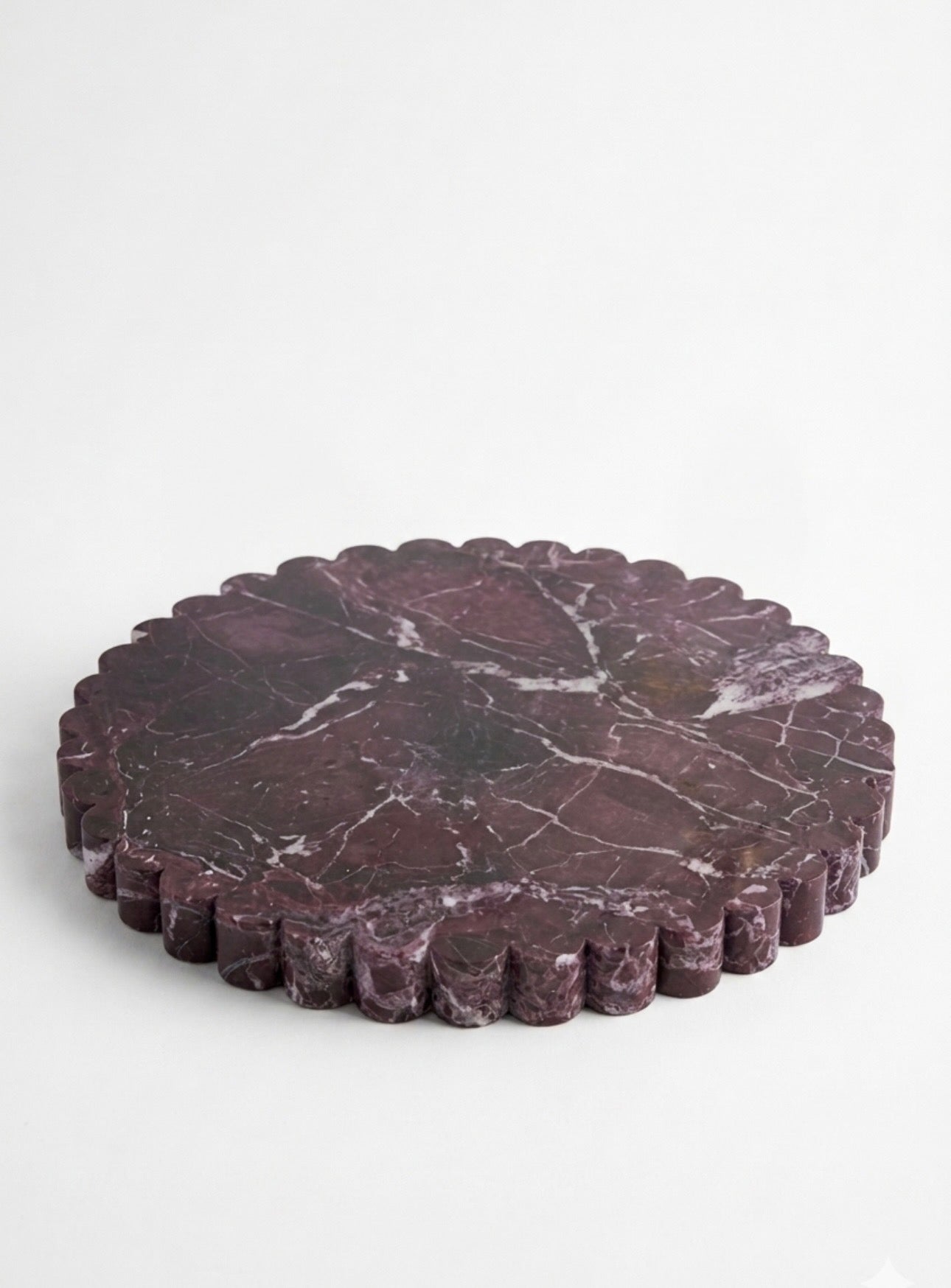 Round dark marble stone with scalloped edge on a white background